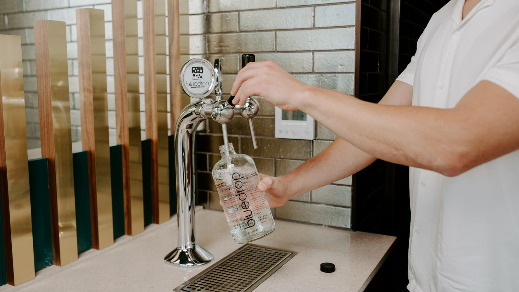 A person filling their water bottle using the tower product.