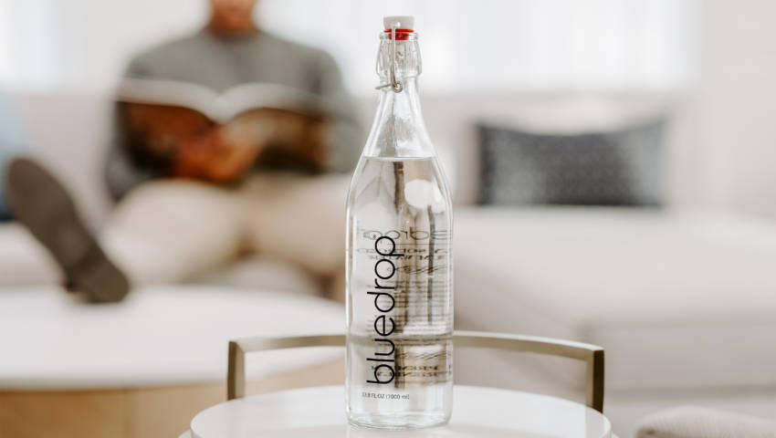 A bottle of bluedrop water on a table in a Brenton hotel room.