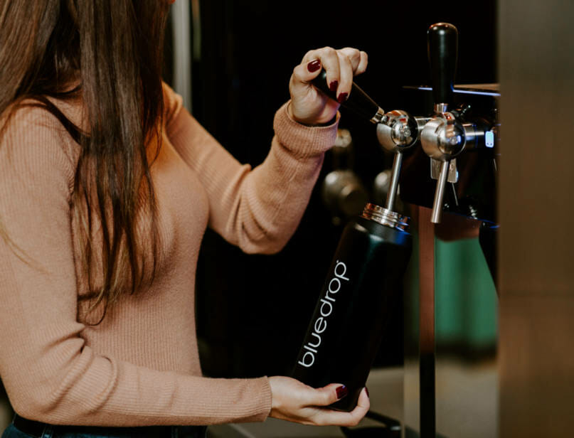 A person filling their water bottle with the Bluedrop product.