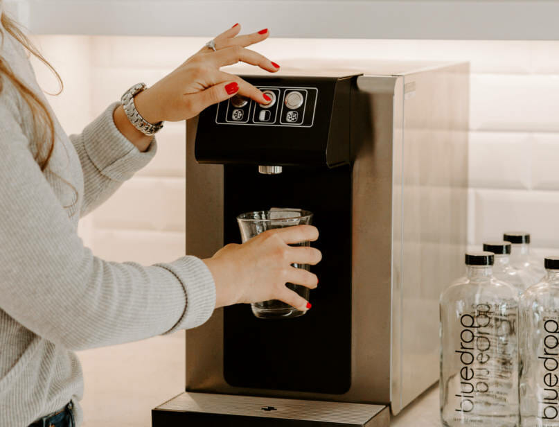 A person using the blue30-hot product to fill a cup with water.