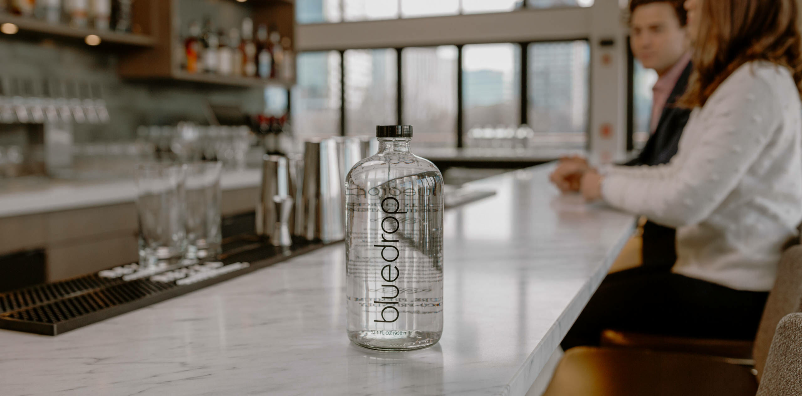 A bluedrop bottle of water sitting on a counter at a bar or restaurant.