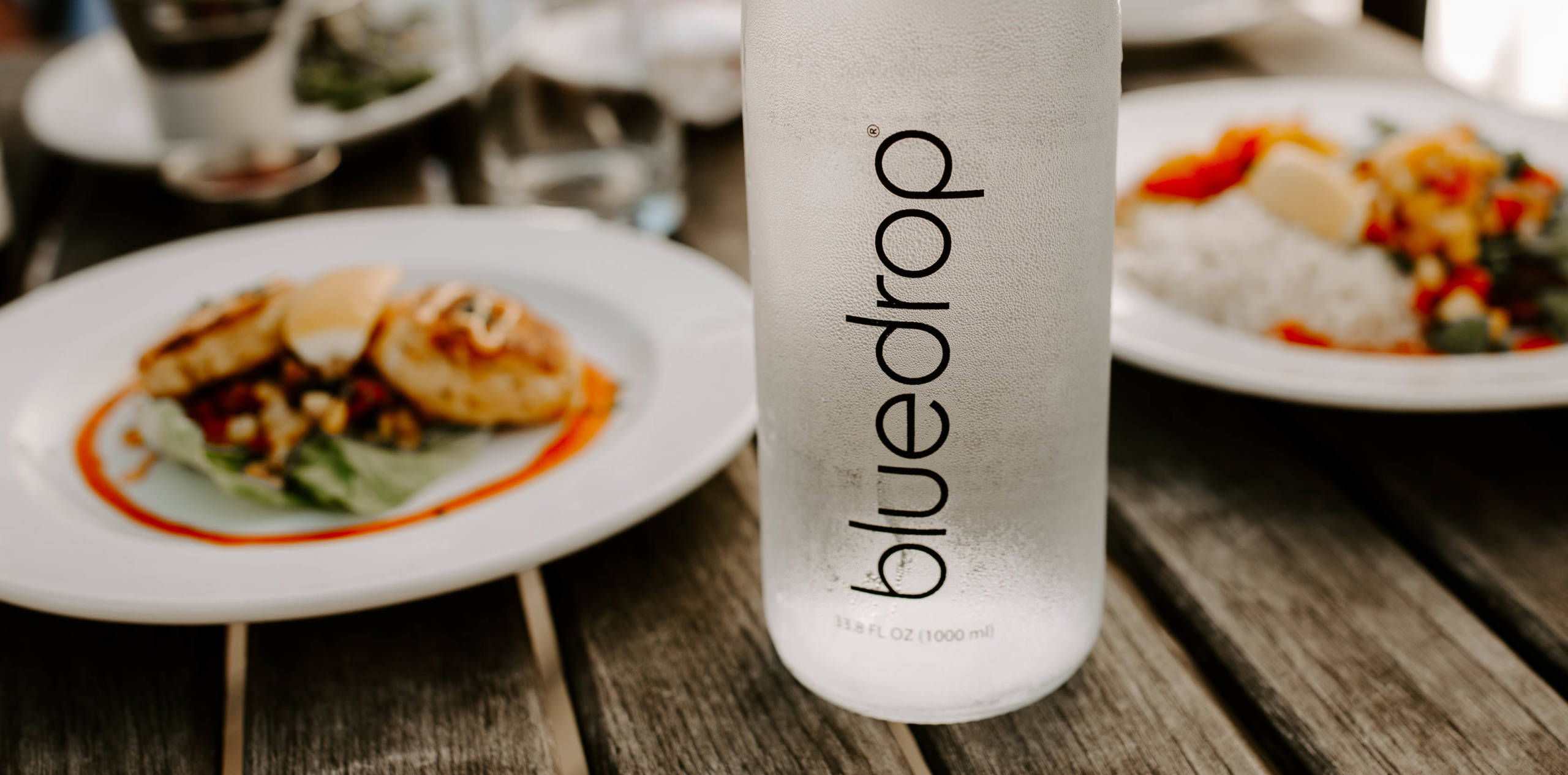 A bottle of bluedrop water on a table at a restaurant.