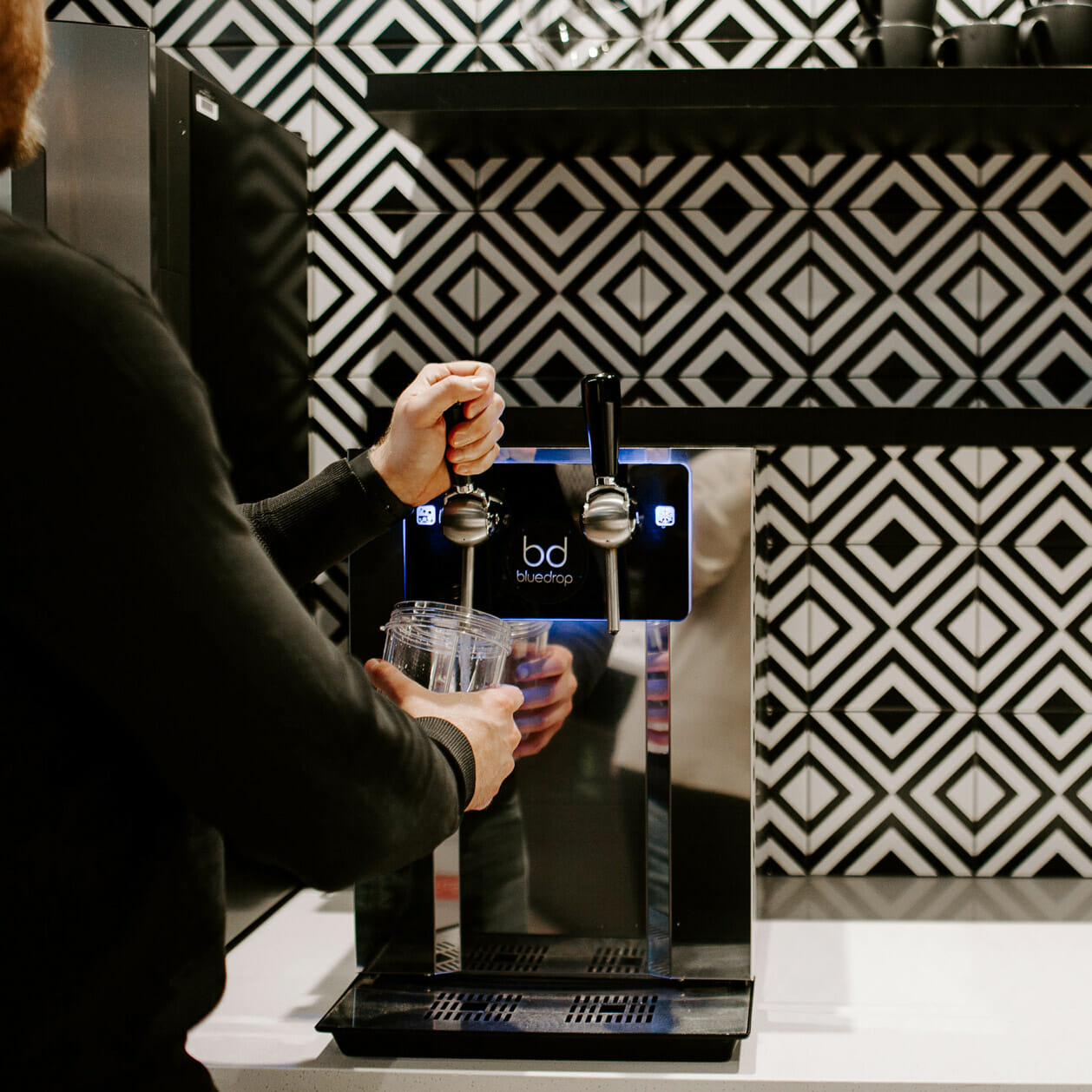 Person using the Bar90 product to fill a glass with water.