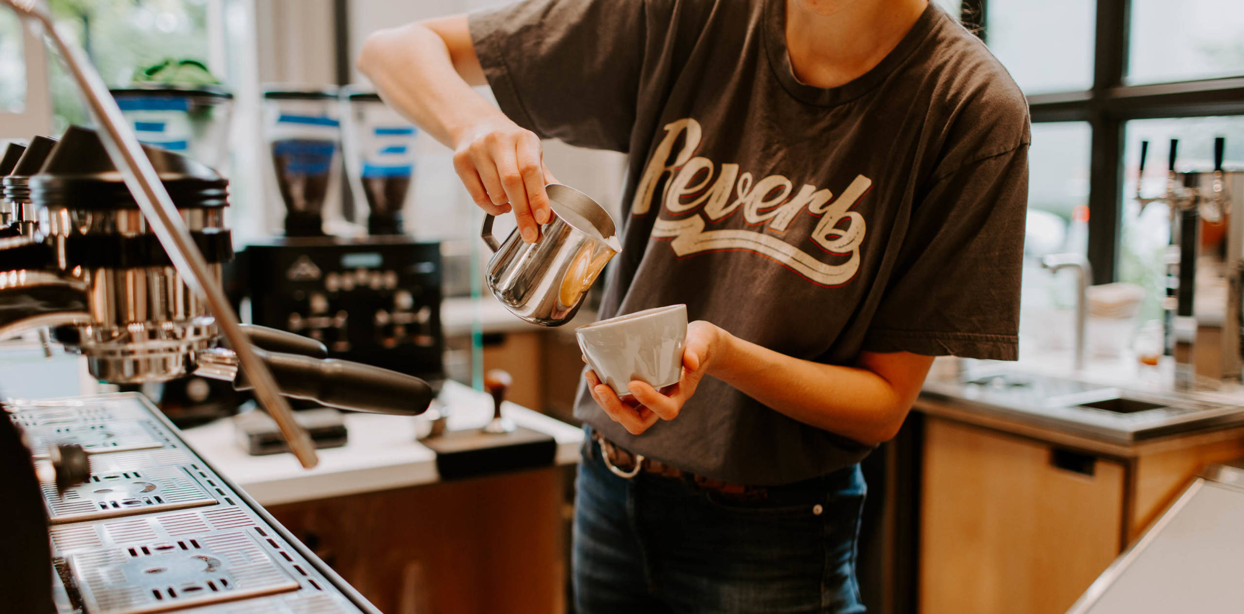 A person making a latte after using the filtration equipment.