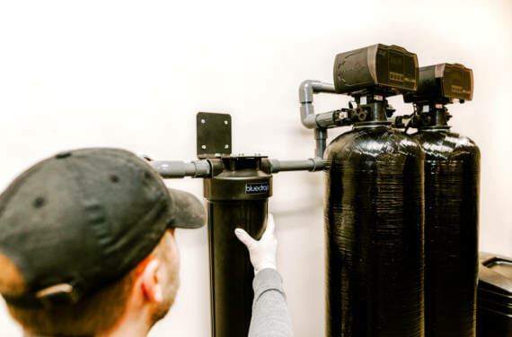 A person installing or adjusting their bluedrop water filtration system.