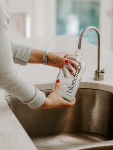 A person filling their bluedrop water bottle with water from their tap.