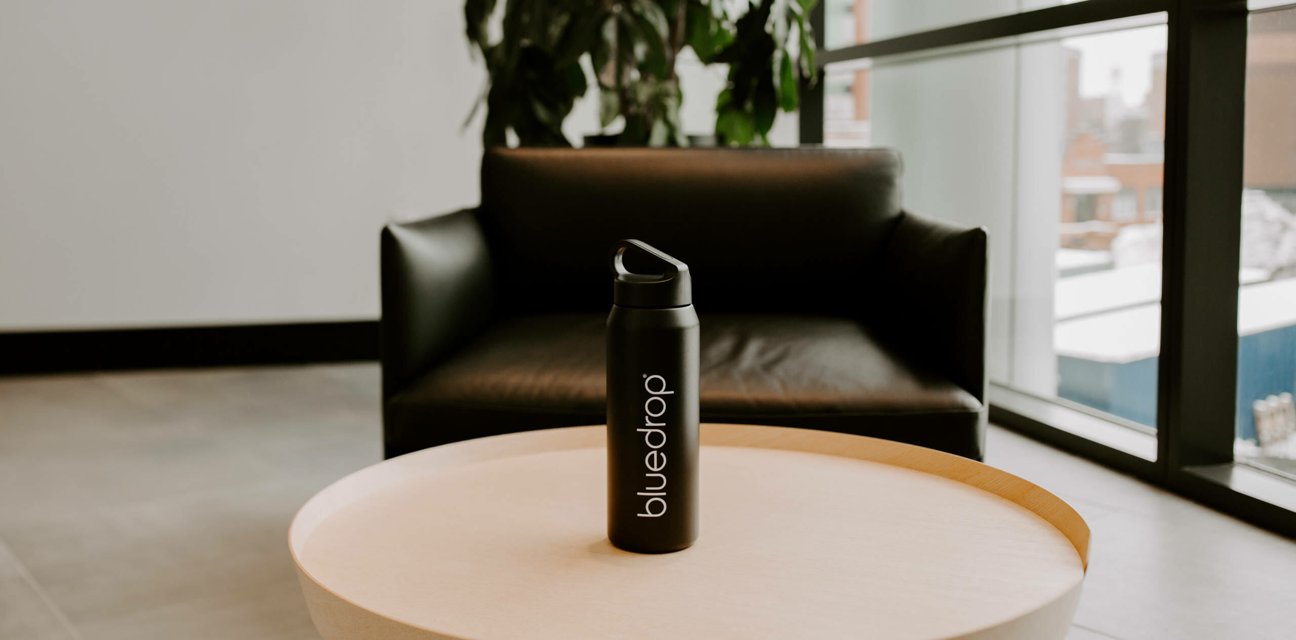 A bluedrop water branded bottle sitting on a table.