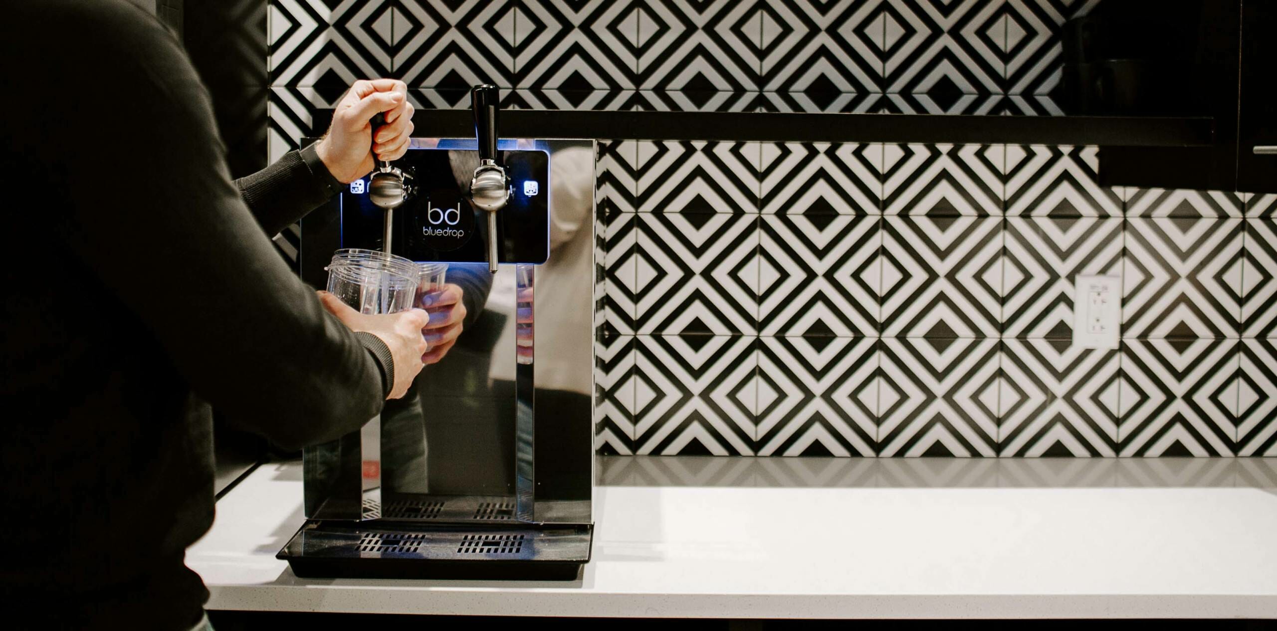 A person using a bluedrop water product to fill up their water glass.