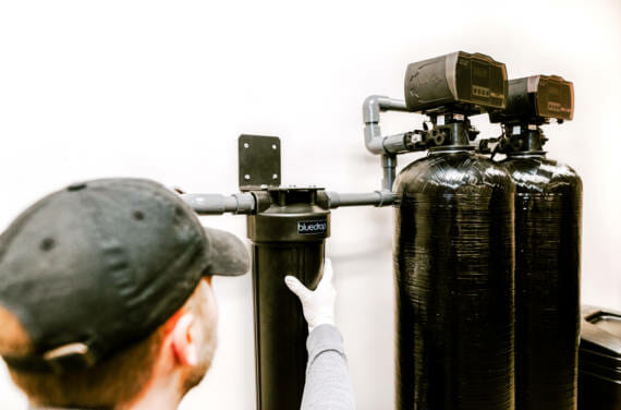 A person adjusting or installing a bluedrop water filtration system.