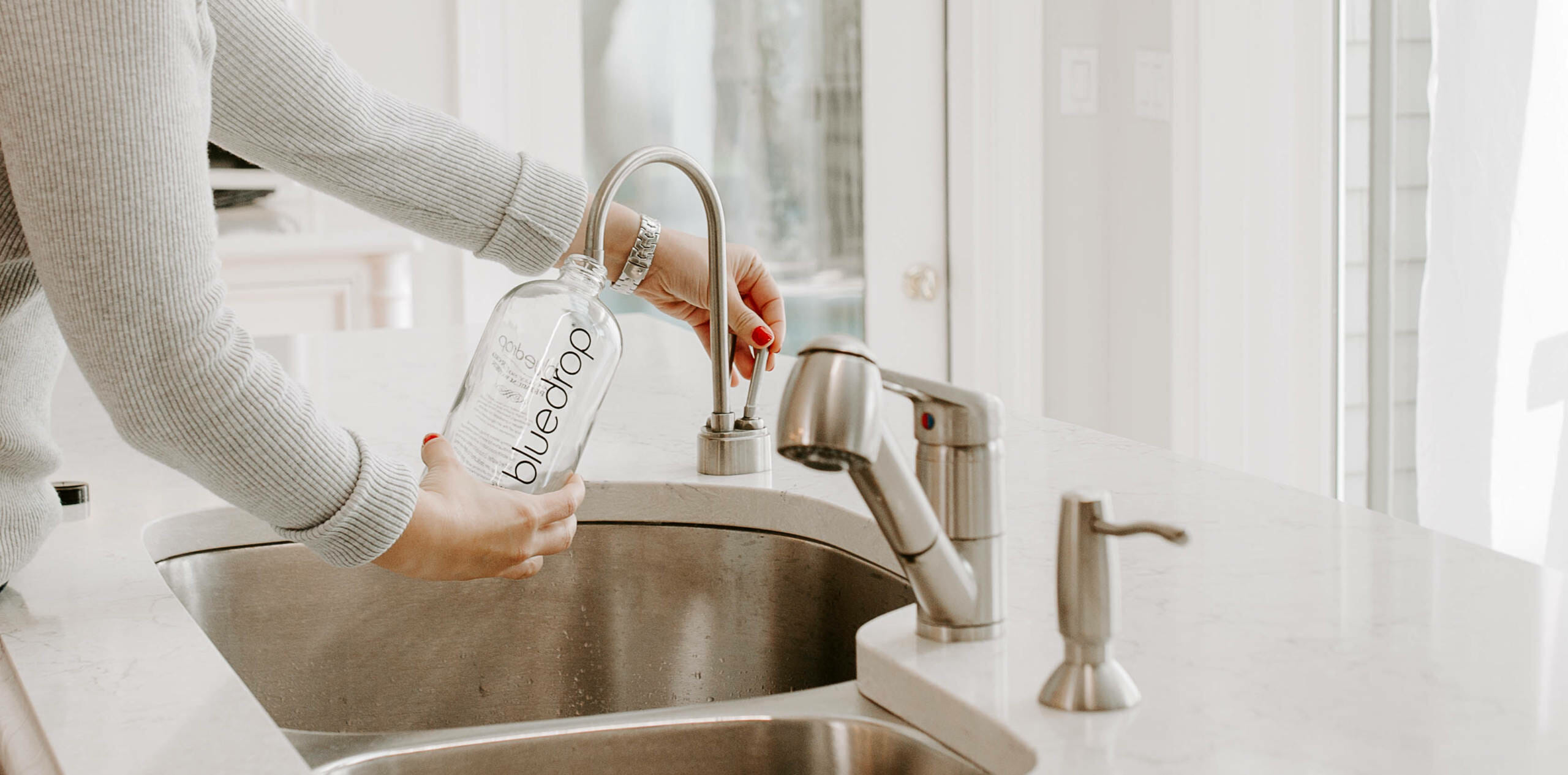 A person using their home drinking water filtration system from bluedrop water.